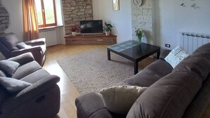 Una sala de estar con pared de piedra, televisión y chimenea.