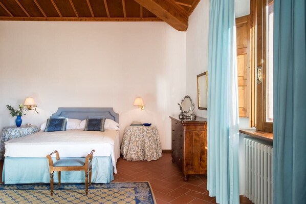 A bedroom with a bed, bedside tables, a dresser, a chair, and a window with curtains.