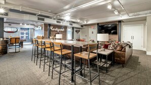 A spacious room with a long table and chairs, a sofa, and a brick accent wall. - Honky Tonk Suite/6 BR/3600sqft, Walkto Broadway (Nashville)