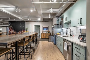 A modern kitchen with a long wooden table, bar stools, and a built-in oven.