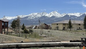 A rural setting with a wooden cabin, a fenced area, and a mountain range in the background. - Historic Westcliffe Outpost Loft (Westcliffe)