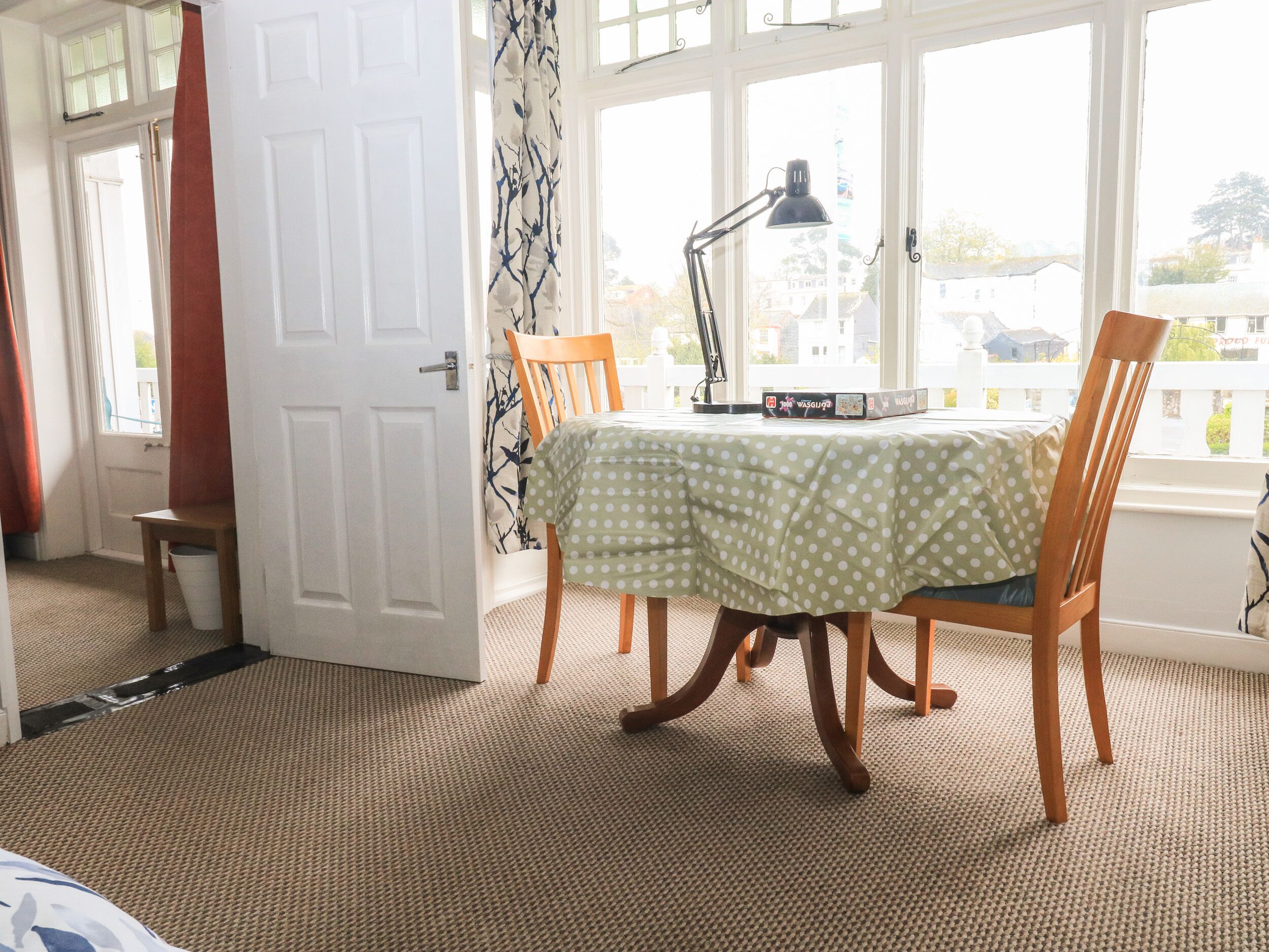 Quarto com mesa de jantar, cadeiras, luminária e janela com vista para casas.