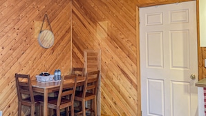 A room with a wooden herringbone ceiling, a white door, and a dining area with wooden chairs and a table. - Ahmic Lake Resort's 1-Bedroom Cottage w/ hot tub (LOON Cottage) (Magnetawan)