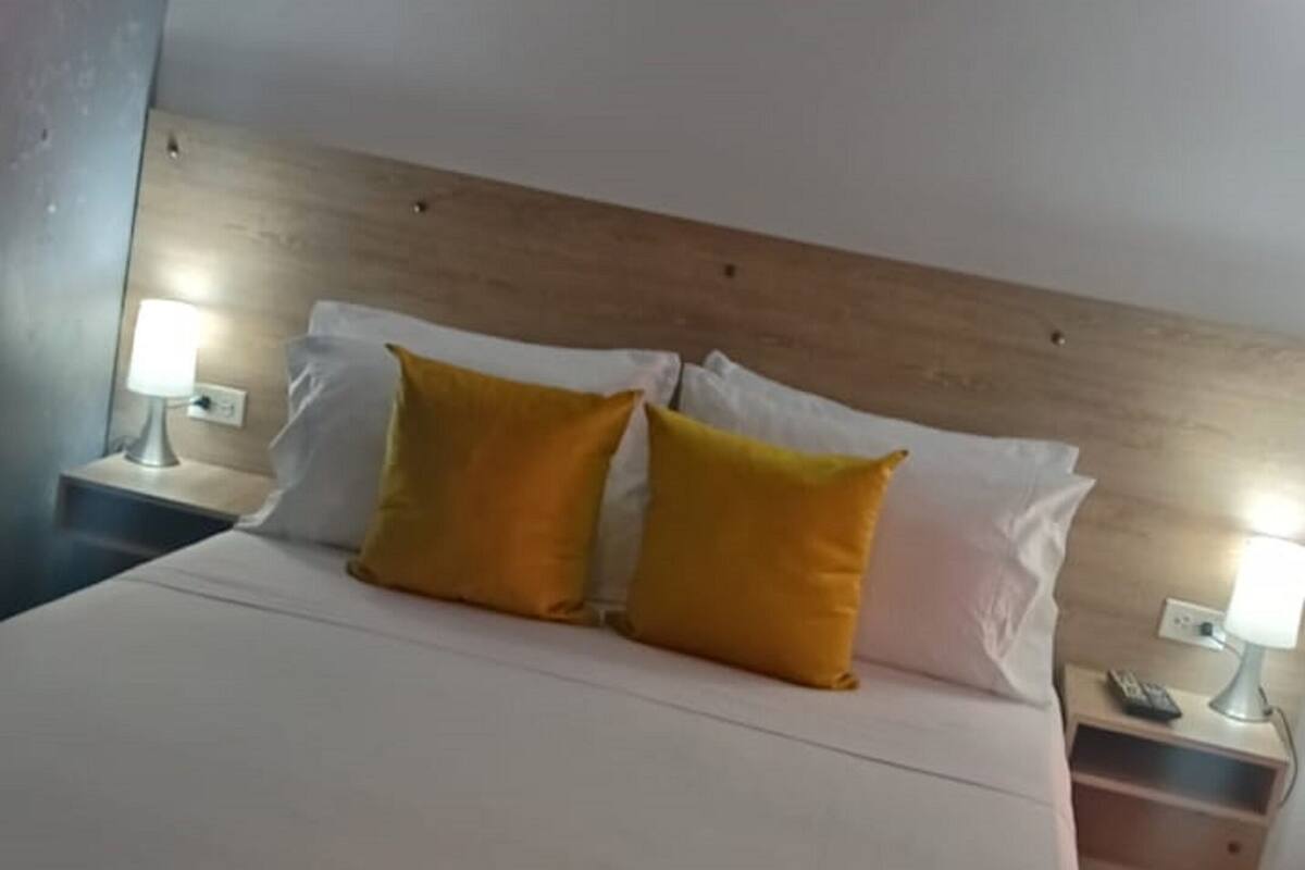 A hotel room with a large bed, two bedside tables, and a wooden headboard.