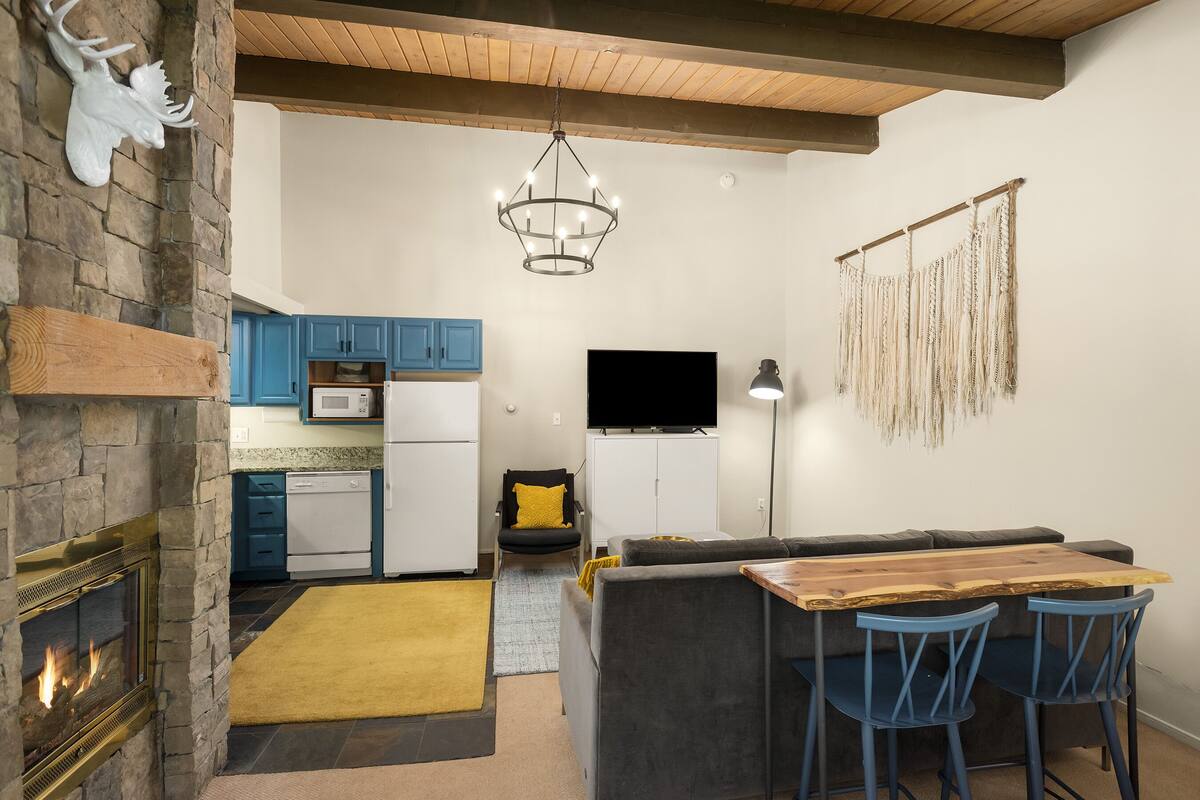 Una cocina moderna con armarios azules, una chimenea de piedra y techo de madera.