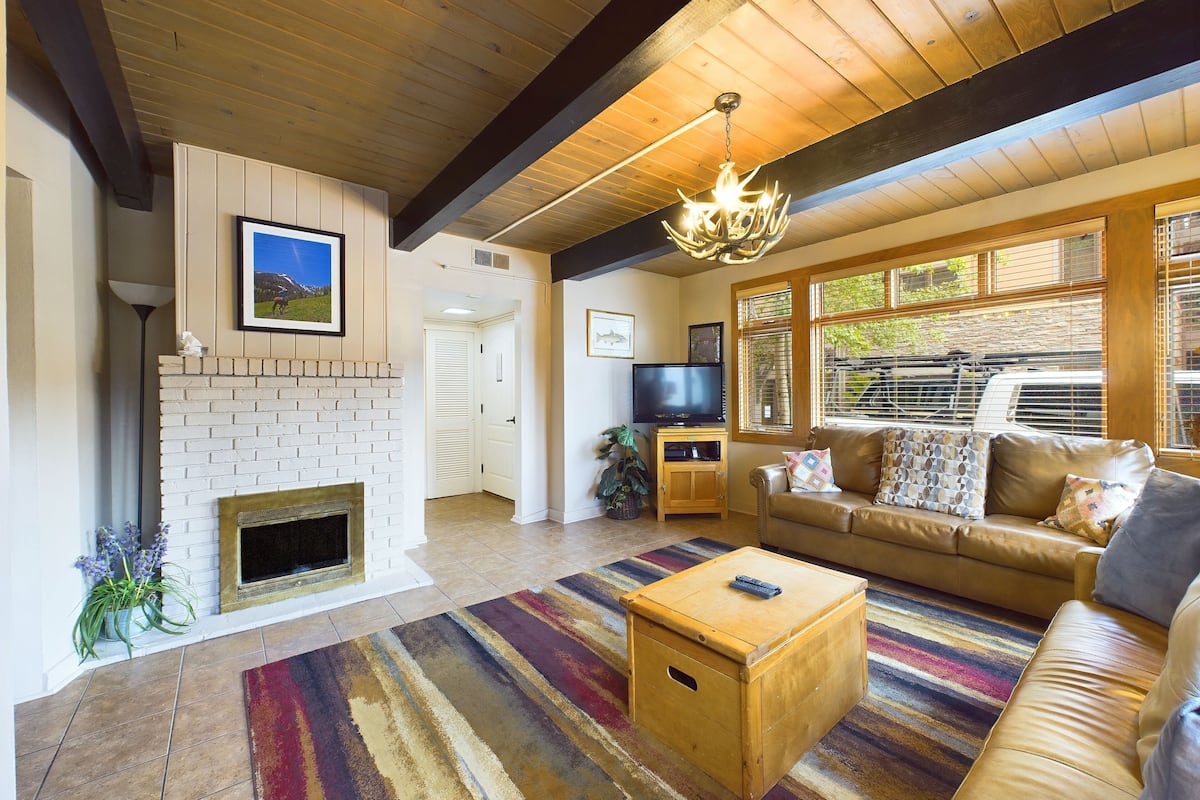 Una sala de estar con chimenea, un sofá, un televisor y una mesa de centro de madera.