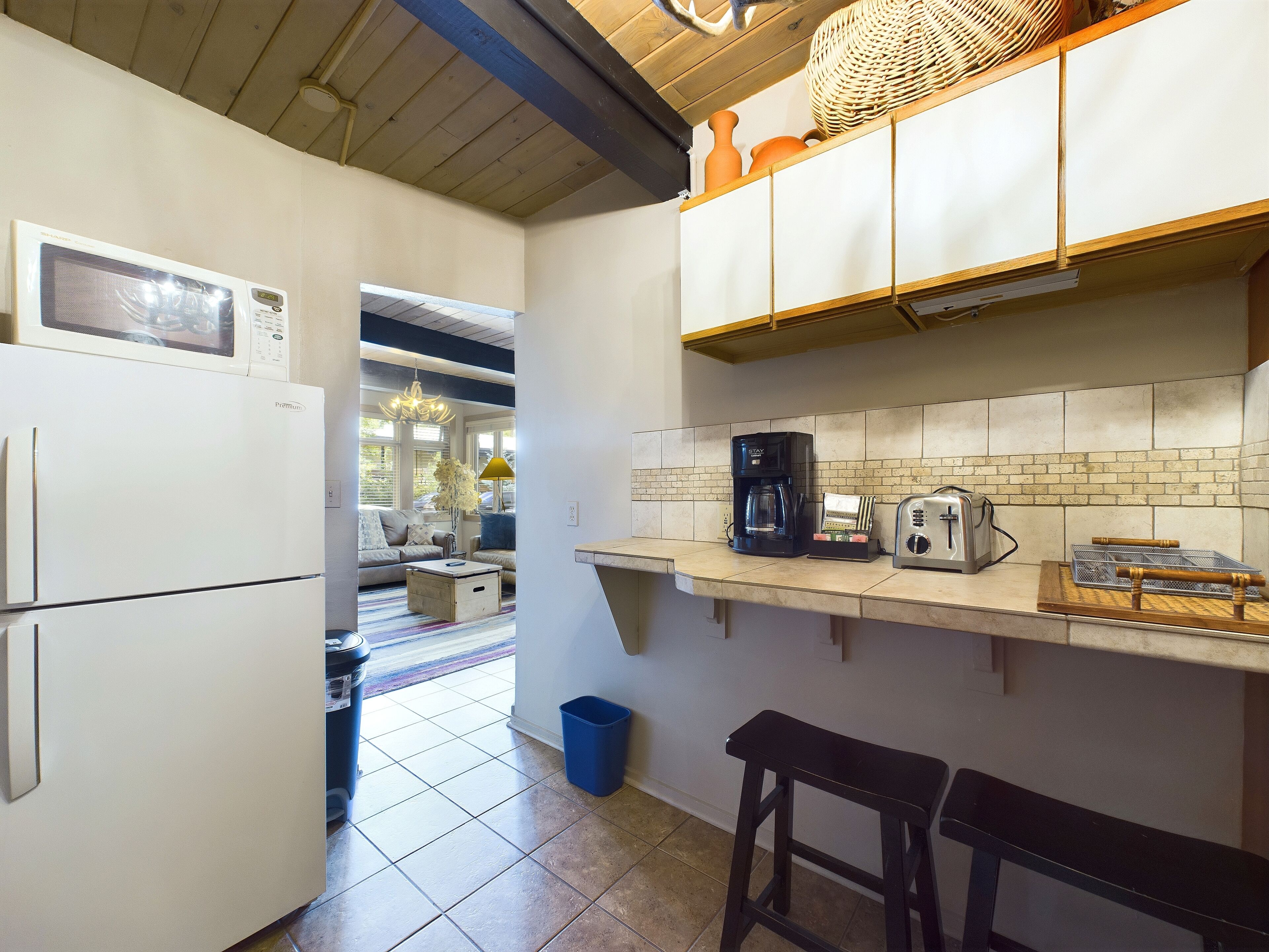 A kitchen with a microwave, coffee maker, toaster, and a wicker basket on the counter.