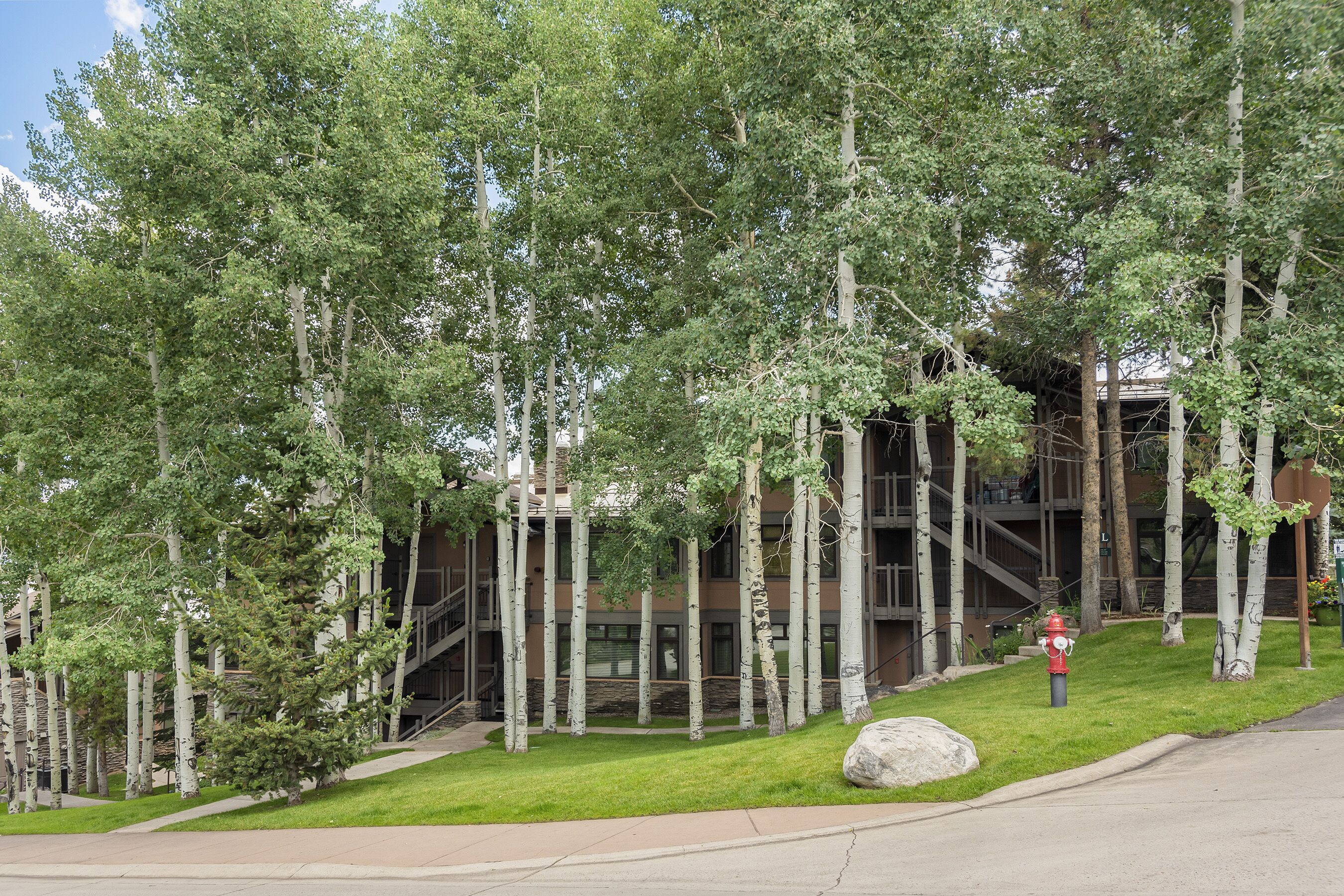 Un bâtiment à l’architecture moderne, entouré d’une pelouse bien entretenue et de grands arbres.