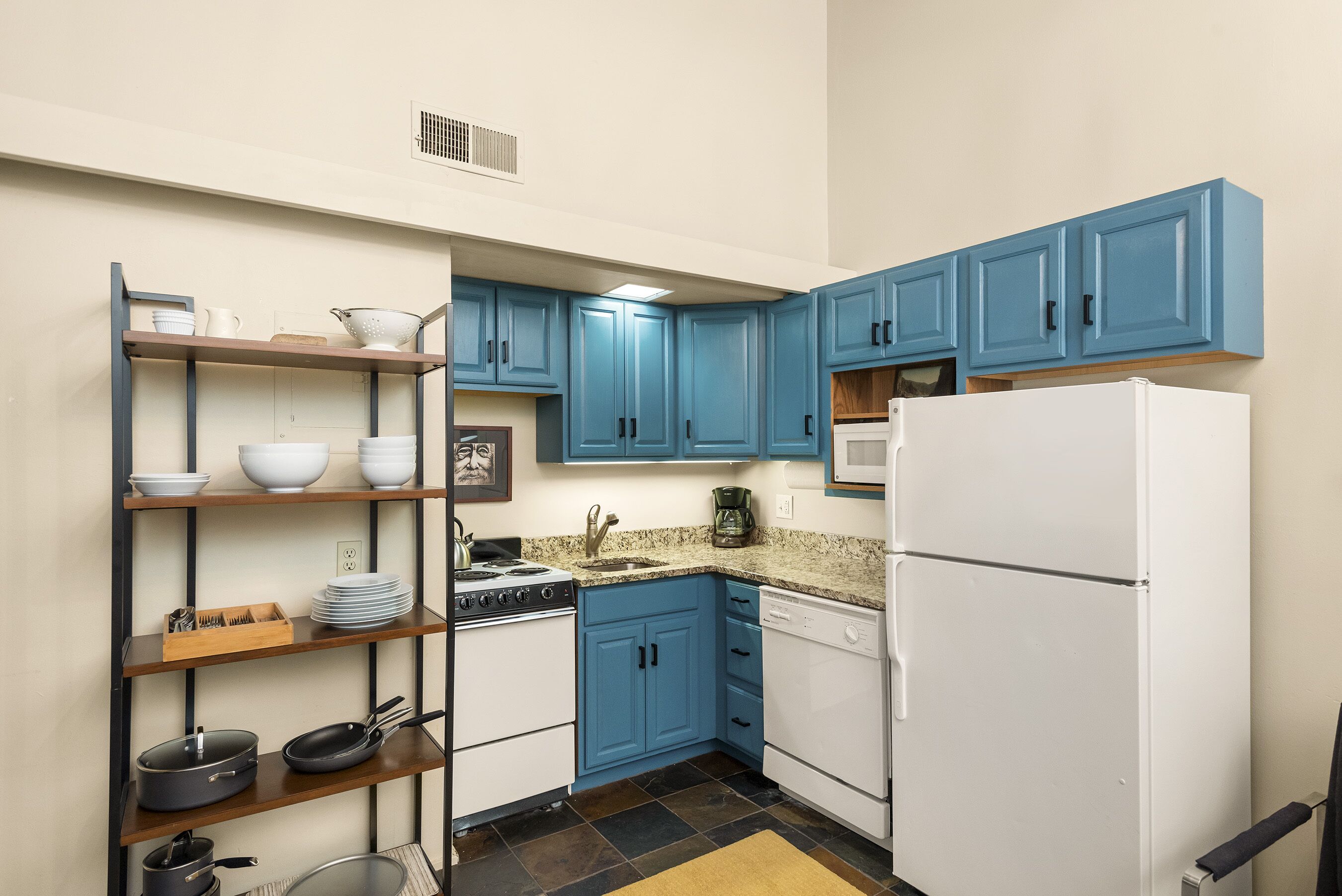 A compact kitchen with blue cabinets, a white refrigerator, and a stove.