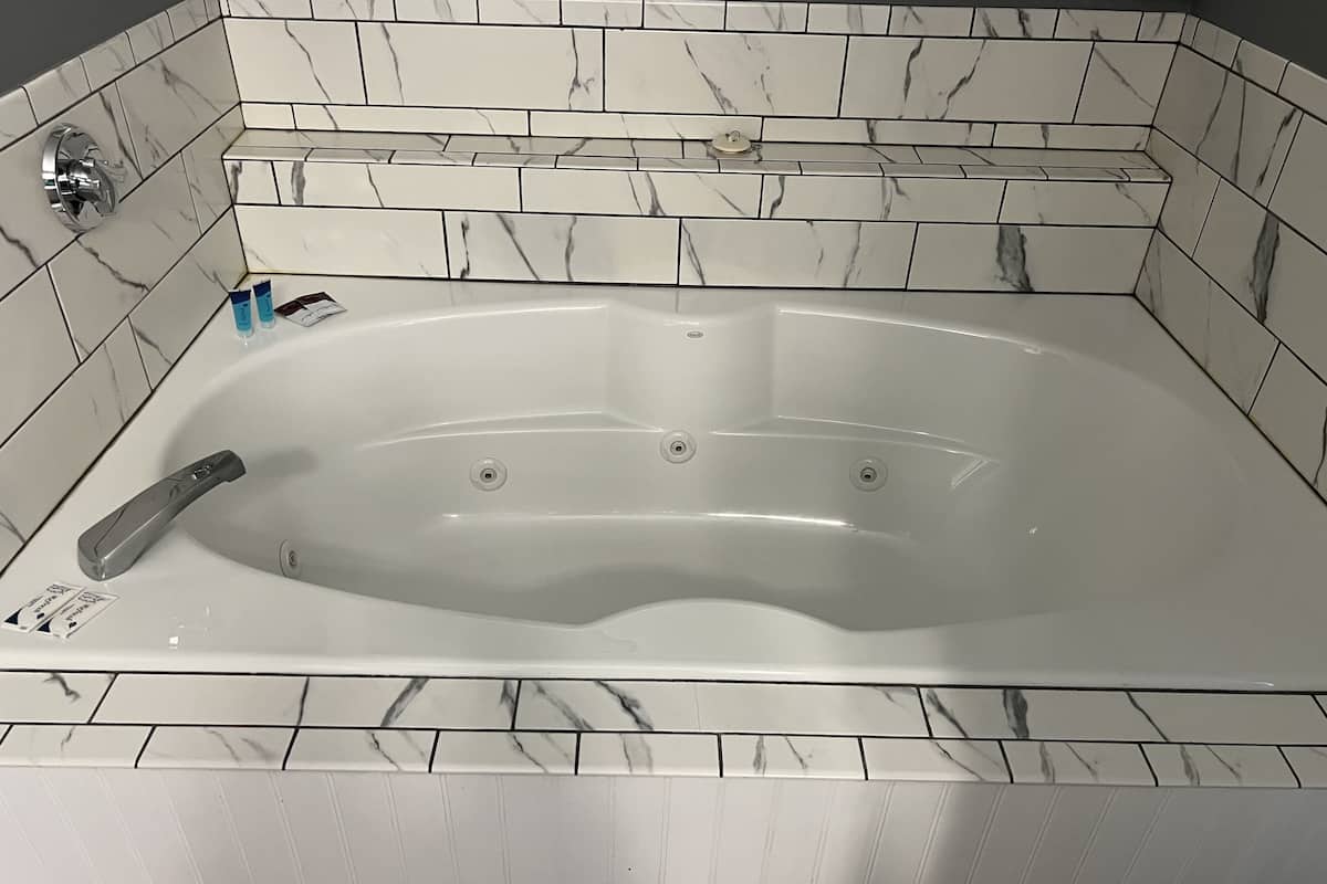 A modern bathroom with a freestanding bathtub, marble tiles, and a chrome faucet.