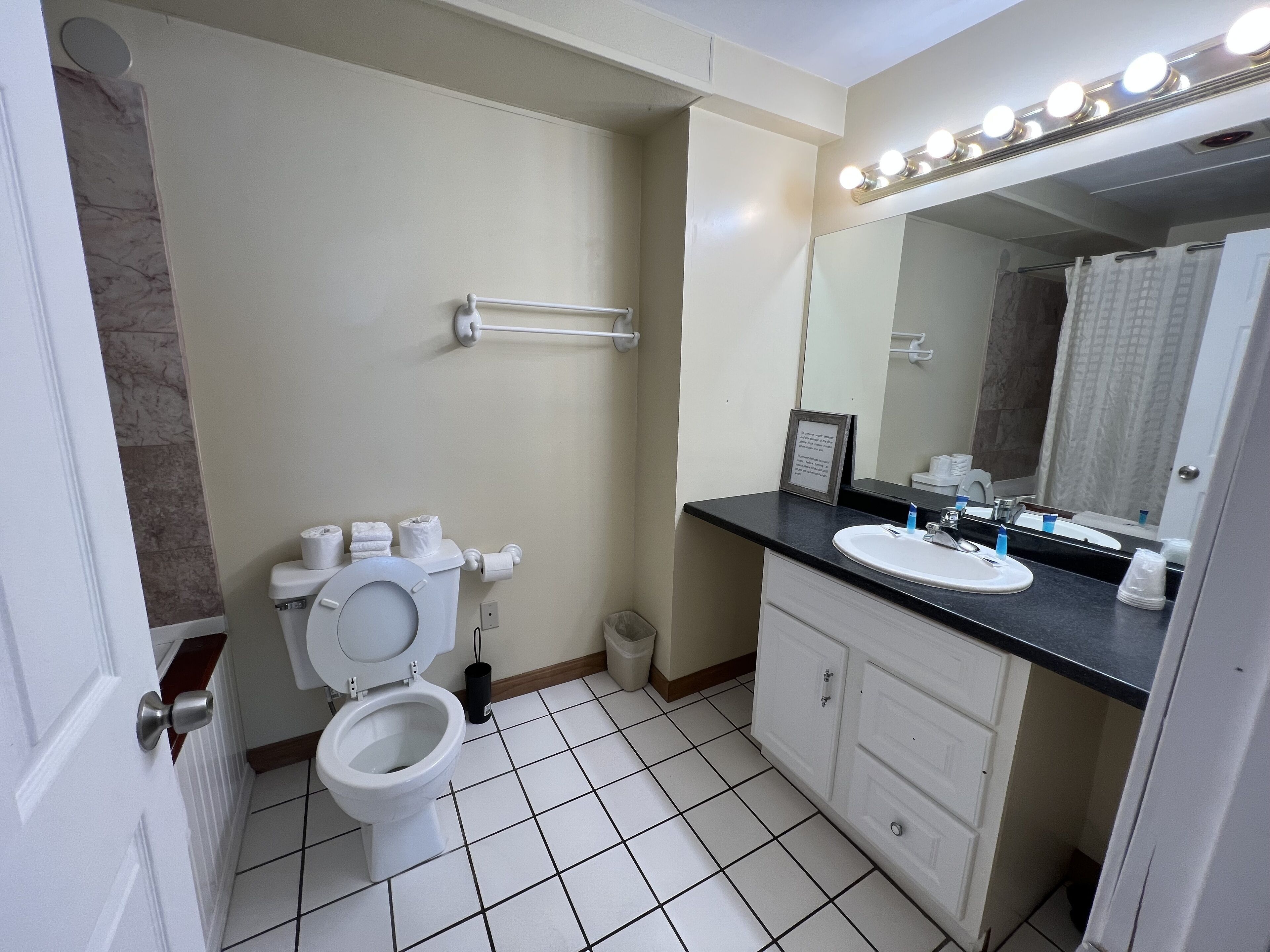 Et badeværelse med toilet, håndvask, underskab og et spejl med lys.