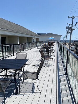 A deck with outdoor seating, a railing, and a view of the ocean. - SHIPS INN Hotel (Hampton)