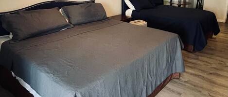 Una camera da letto con un letto grande, un letto più piccolo e una piccola cucina sullo sfondo.