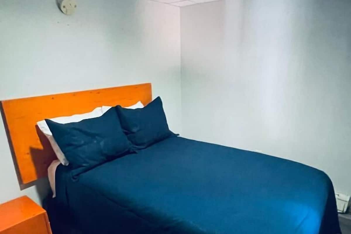 A single bed with a wooden headboard and a dark blue bedspread.