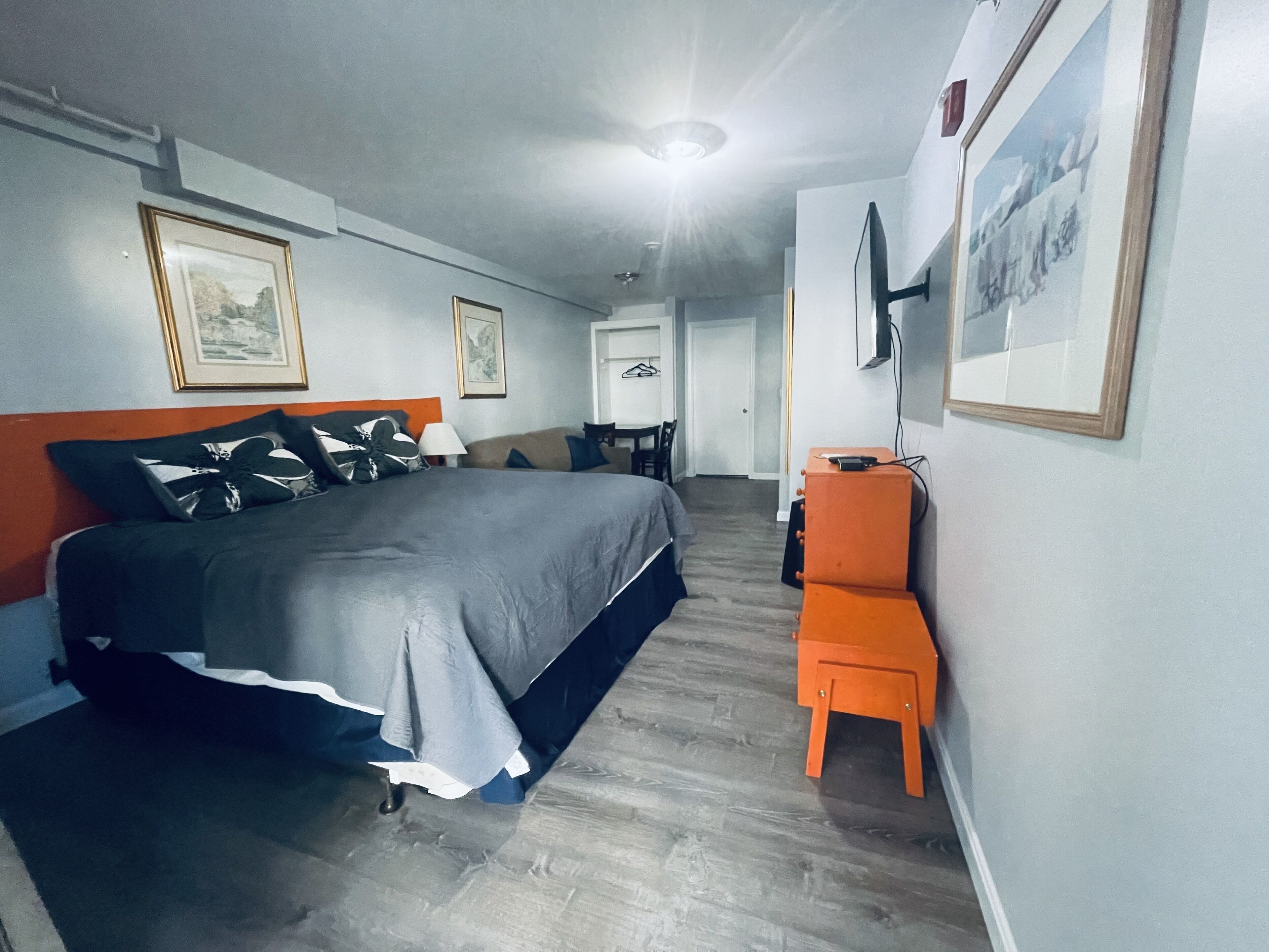 A hotel room with a bed, a desk, and a chair. There are framed pictures on the walls.