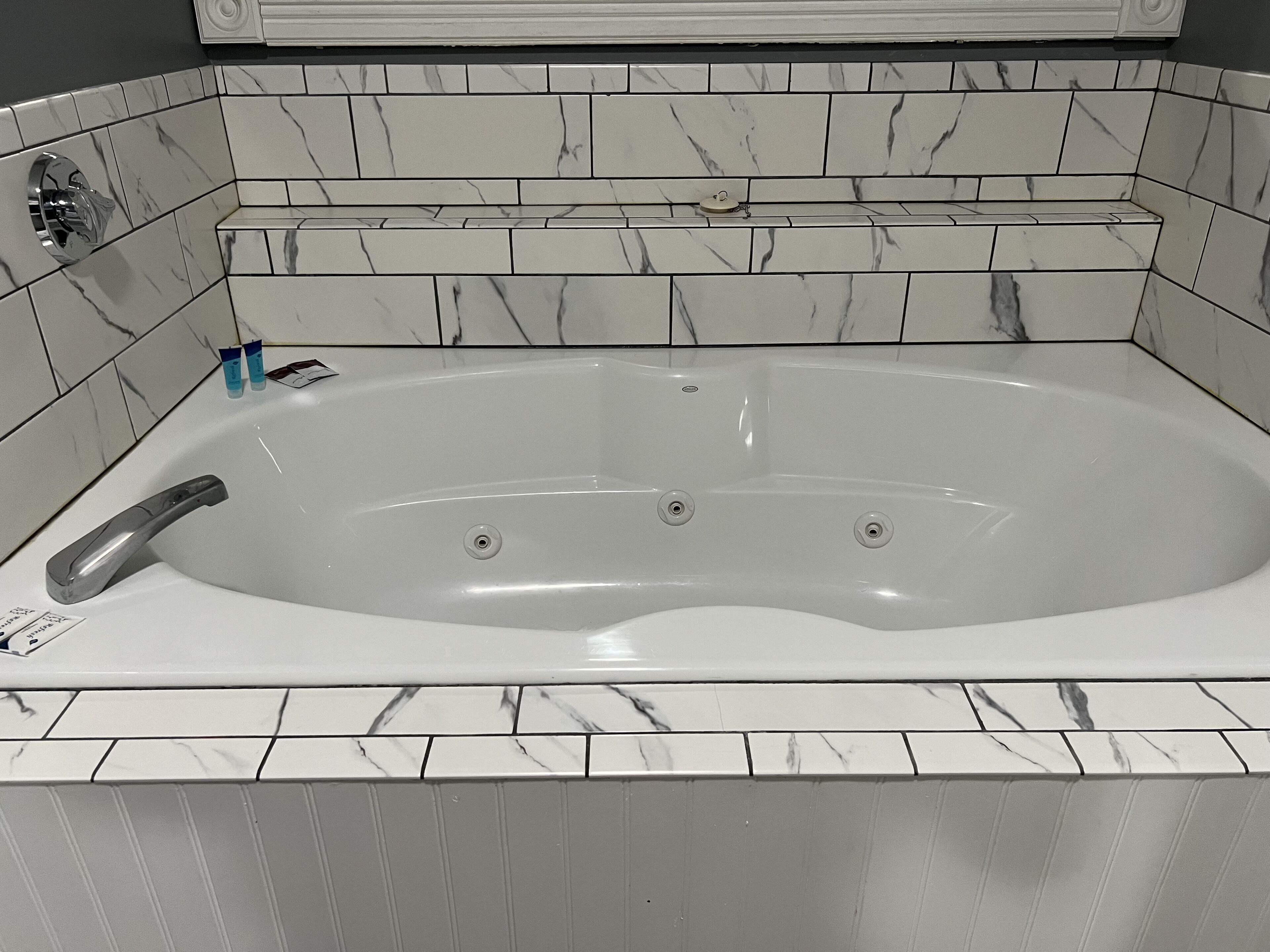 Un baño moderno con pared revestida de mármol y una bañera independiente.