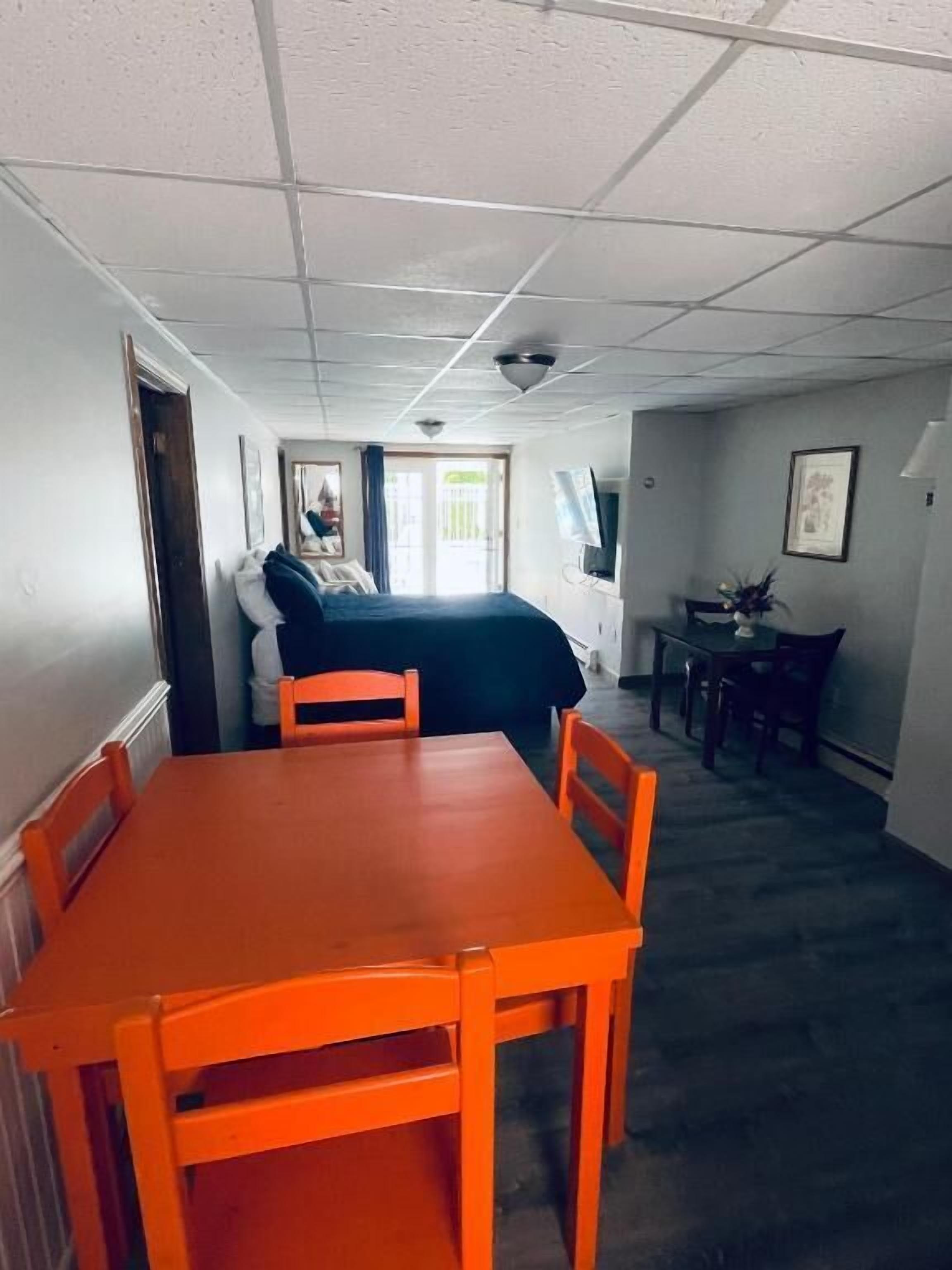 A room with a bed, a small table with chairs, a TV, and a window.