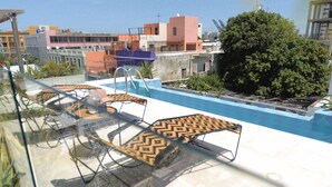 A rooftop pool area with lounge chairs and a small wicker basket. - NEW Stylish Colonial House with Pool and Rooftop (Santa Marta)