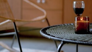 A wicker chair and a small round table with a candle and a glass of red wine. - NEW Stylish Colonial House with Pool and Rooftop (Santa Marta)