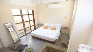 A bedroom with a bed, bedside tables, a mirror, a potted plant, and a window. - NEW Stylish Colonial House with Pool and Rooftop (Santa Marta)