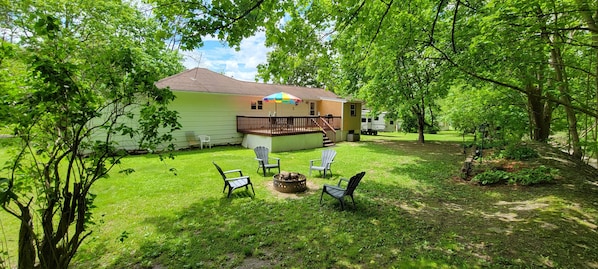 A single-story house with a fenced deck, outdoor seating, and a fire pit. - Al's Creekside Cottage in the Finger Lakes (Montour Falls)