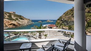A balcony with a pool, chairs, and a view of the sea and rocky coastline. - Made By The Sea Villa 5 (Malevizi)