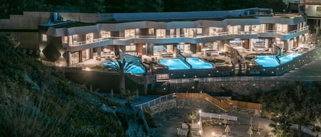 Een meerlaags hotel met een zwembad, terras en uitzicht op het omliggende landschap.