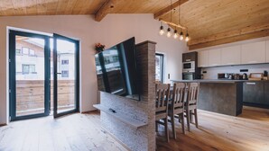 Una cocina moderna con televisor integrado, piso de madera y una zona de comedor con sillas.