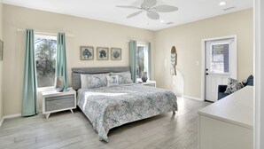 A bedroom with a bed, nightstands, a ceiling fan, and a door.