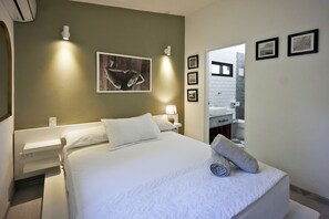 A hotel room with a bed, a nightstand, a lamp, a towel, and a framed picture on the wall. - Villa Taleona (Cóbano)