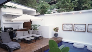 A modern outdoor living area with a pool, a barbecue grill, a sofa, and a chair. - Villa Taleona (Cóbano)