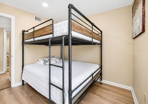 Ein Stockbett in einem Zimmer mit Holzboden und beige gefärbten Wänden.