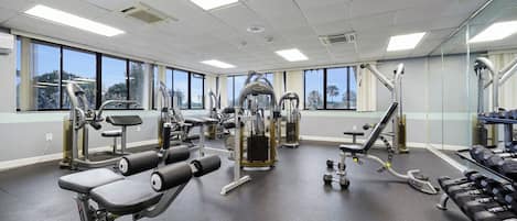 A gym with various exercise equipment, large windows, and a clean, modern design.