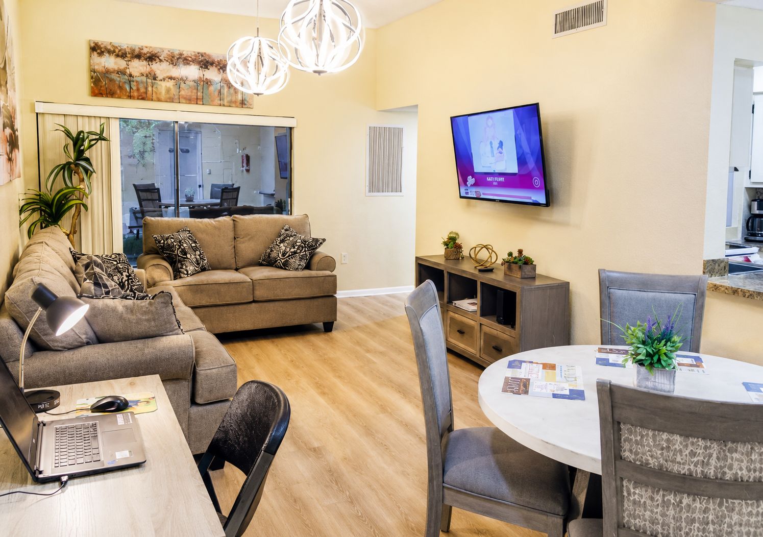 Una sala de estar moderna con un sofá, una mesa de comedor y un televisor montado en la pared.