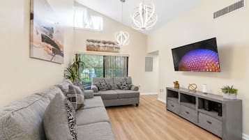 A modern living room with a sectional sofa, a flat-screen TV, and a minimalist design.