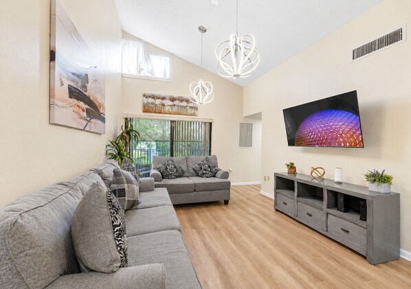 A modern living room with a sectional sofa, a flat-screen TV, and a minimalist design.