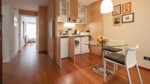 A compact kitchen with modern appliances, a dining area with a glass table, and a living space with a sofa and a TV. - Bravissimo Casa Magnolia, one-bedroom apartment near Girona’s ancient wall (Girona)