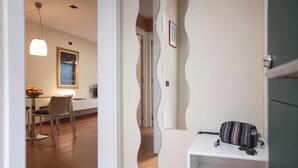 A modern interior with a unique wall design, a dining area with a table and chairs, and a white shelf with bags and shoes. - Bravissimo Casa Magnolia, one-bedroom apartment near Girona’s ancient wall (Girona)