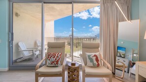 A room with two chairs, a small table, a TV, and a balcony with a view. - Sandcastle Condominium Unit 111 (Port Aransas)