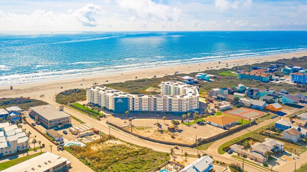 Um hotel à beira-mar com vários edifícios, acesso direto à praia e uma estrada que leva até ela.
