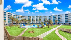 A resort with multiple buildings, a central pool area with lounge chairs, and a well-maintained lawn. - Sandcastle Condominium Unit 137 (Port Aransas)