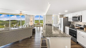 A modern kitchen with a granite countertop, stainless steel appliances, and a view of the outdoors. - Sandcastle Condominium Unit 137 (Port Aransas)
