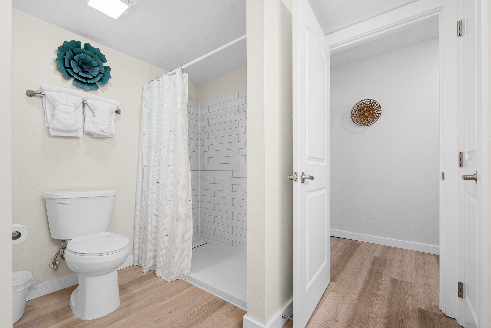 A bathroom with a toilet, shower, and a door leading to another room.
