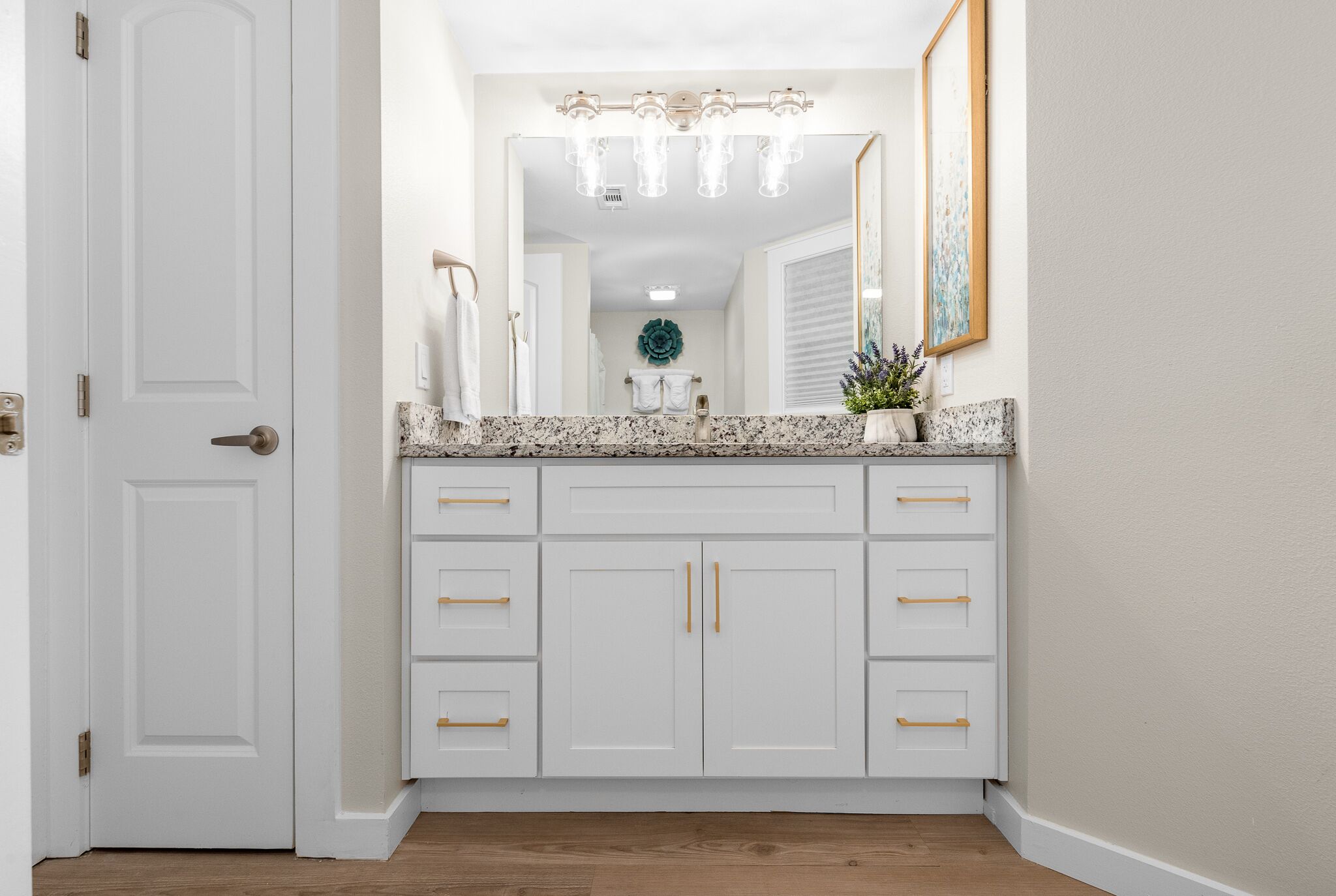 A bathroom with a white vanity, a large mirror, and a light fixture above the mirror.