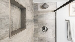 Een moderne badkamer met een douche, een inbouwspiegel en een handdoekrek.