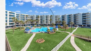 A hotel with a swimming pool, multiple balconies, and a well-maintained lawn. - Sandcastle Condominium Unit 237 (Port Aransas)