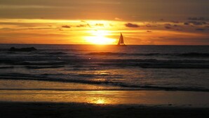 A sunset over the ocean with a sailboat in the distance. - Beachfront One Bedroom on Tamarindo Beach (Tamarindo)