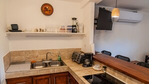 A kitchen with a countertop, sink, cabinets, and a stove. - Beachfront One Bedroom on Tamarindo Beach (Tamarindo)