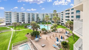 A hotel with multiple floors, a central pool, and outdoor seating areas. - Sandcastle Condominium Unit 311 (Port Aransas)