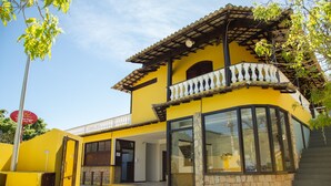 Un edificio amarillo con piscina, balcón y pared de piedra.